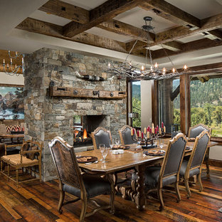 Dining room - large rustic dark wood floor dining room idea in Other with white walls, a two-sided fireplace and a stone fireplace
