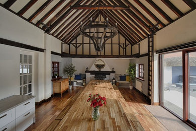 Inspiration for a large country dining room in Other with white walls, dark hardwood flooring, a standard fireplace, a brick fireplace surround and brown floors.