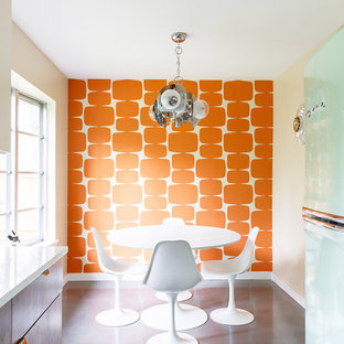 Idee per una sala da pranzo aperta verso la cucina moderna con pavimento in cemento, pareti arancioni, nessun camino e pavimento grigio