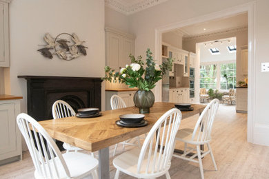 Idées déco pour une grande salle à manger ouverte sur la cuisine contemporaine avec un mur gris, parquet clair, une cheminée standard et un sol blanc.