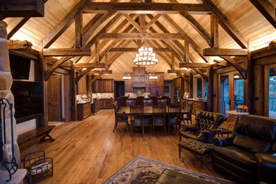 Example of a large mountain style medium tone wood floor great room design in Nashville with brown walls, a standard fireplace and a stone fireplace
