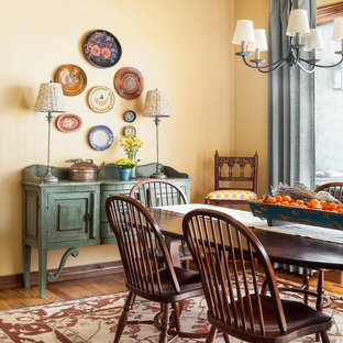 Modelo de comedor de estilo americano con paredes amarillas, suelo de madera en tonos medios y suelo marrón
