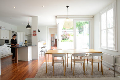 Idée de décoration pour une grande salle à manger ouverte sur la cuisine design avec un mur blanc et un sol en bois brun.
