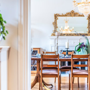 Design ideas for a classic enclosed dining room in London with white walls, medium hardwood flooring, a standard fireplace and brown floors.