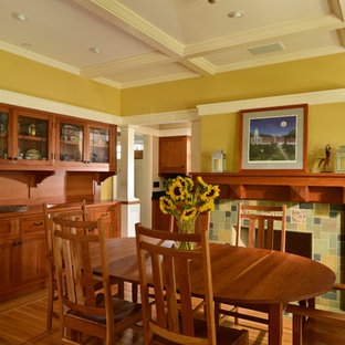 Imagen de comedor de estilo americano con paredes amarillas, suelo de madera en tonos medios, chimenea tradicional y marco de chimenea de baldosas y/o azulejos