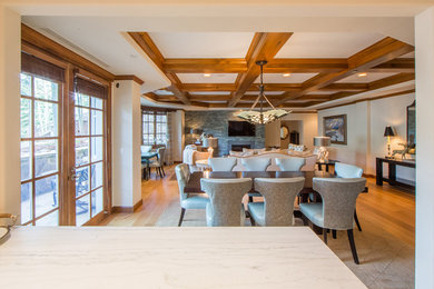 Example of a large transitional medium tone wood floor, coffered ceiling and brown floor great room design in Denver with beige walls, a standard fireplace and a stone fireplace