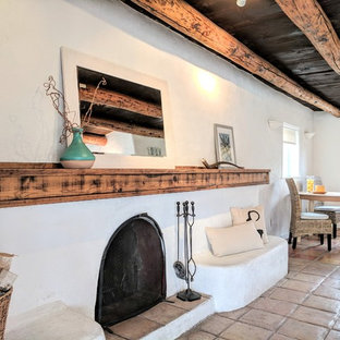 Modelo de comedor de cocina de estilo americano, de tamaño medio, con paredes blancas, suelo de baldosas de terracota, chimenea tradicional, marco de chimenea de hormigón y suelo beige
