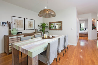 Exemple d'une salle à manger ouverte sur la cuisine exotique de taille moyenne avec un mur blanc, un sol en bois brun et aucune cheminée.