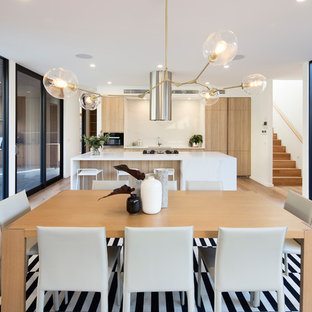 Inspiration for a contemporary kitchen/dining combo in Melbourne with white walls, medium hardwood floors and brown floor.