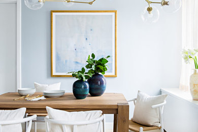 Ejemplo de comedor costero con paredes azules, suelo de madera clara y suelo beige