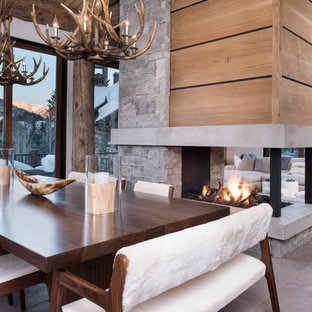 Immagine di una sala da pranzo aperta verso il soggiorno contemporanea di medie dimensioni con pareti beige, pavimento in ardesia, camino bifacciale, cornice del camino in pietra e pavimento grigio