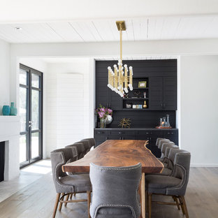 Ispirazione per una grande sala da pranzo aperta verso il soggiorno minimalista con pareti bianche, parquet chiaro, camino classico e cornice del camino in mattoni