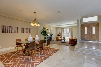 This is an example of a medium sized traditional open plan dining room in Los Angeles with beige walls, porcelain flooring, a standard fireplace, a stone fireplace surround and grey floors.