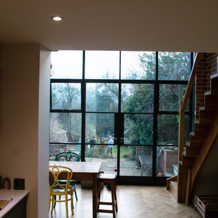 Foto di una grande sala da pranzo aperta verso la cucina industriale con pareti multicolore, pavimento in legno massello medio, pavimento marrone e pareti in mattoni