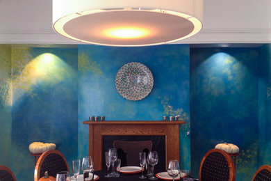 Imagen de comedor minimalista de tamaño medio cerrado con paredes azules, suelo de madera oscura, todas las chimeneas y marco de chimenea de madera