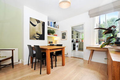 Small nautical enclosed dining room in Surrey with white walls and light hardwood flooring.