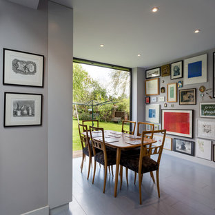 Immagine di una sala da pranzo aperta verso la cucina minimal di medie dimensioni con pareti bianche, pavimento in legno verniciato e pavimento grigio