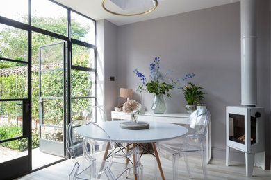 Idée de décoration pour une salle à manger ouverte sur le salon urbaine avec un mur gris, un sol en carrelage de porcelaine, un poêle à bois et un sol beige.
