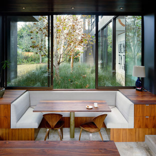 Idee per una sala da pranzo aperta verso la cucina minimalista con pareti nere, pavimento in cemento e nessun camino