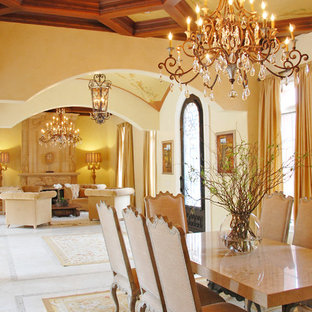 Idee per una grande sala da pranzo aperta verso il soggiorno mediterranea con pareti gialle, pavimento in gres porcellanato, camino classico e cornice del camino in pietra