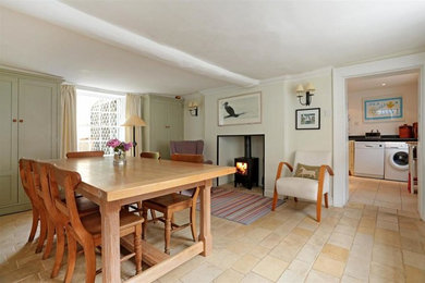 Photo of a country open plan dining room in Wiltshire with limestone flooring, a wood burning stove and beige floors.