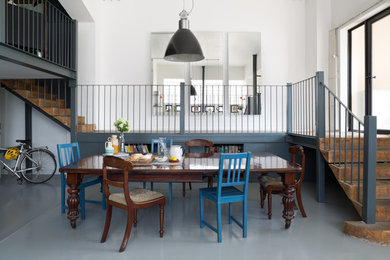 Photo of an industrial kitchen/dining room in London with white walls, painted wood flooring and no fireplace.