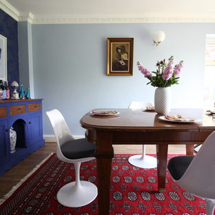 Medium sized bohemian enclosed dining room in Surrey with blue walls, laminate floors and brown floors.