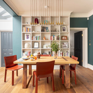This is an example of a contemporary dining room in London with green walls, medium hardwood flooring and brown floors.