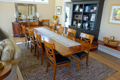 Immagine di una grande sala da pranzo aperta verso il soggiorno tradizionale con pareti beige, parquet chiaro, cornice del camino in pietra e pavimento beige