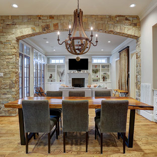 Traditional open plan dining in Houston with beige walls, light hardwood floors, a standard fireplace, a concrete fireplace surround and brown floor.