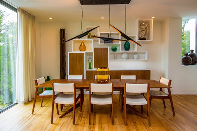 Immagine di una sala da pranzo aperta verso il soggiorno moderna di medie dimensioni con pareti bianche e pavimento in legno massello medio