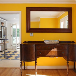 Immagine di una sala da pranzo boho chic con pareti gialle e pavimento in legno massello medio