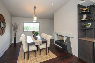 Exemple d'une salle à manger ouverte sur la cuisine tendance de taille moyenne avec un mur gris, parquet foncé et une cheminée double-face.