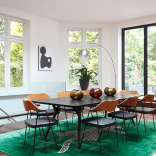 This is an example of a midcentury open plan dining room in London with white walls, dark hardwood flooring and no fireplace.