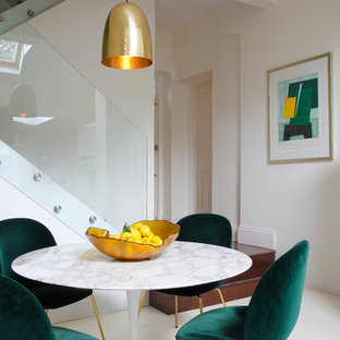 This is an example of a midcentury dining room in London with beige walls, no fireplace and beige floors.
