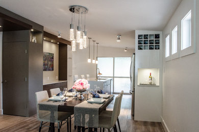 Immagine di una sala da pranzo aperta verso la cucina design di medie dimensioni con pareti bianche e pavimento in legno massello medio