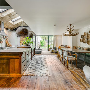 This is an example of an expansive bohemian open plan dining room in London with white walls, medium hardwood flooring and brown floors.