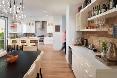 Aménagement d'une salle à manger ouverte sur la cuisine classique de taille moyenne avec un mur multicolore, parquet clair, une cheminée standard et un manteau de cheminée en carrelage.