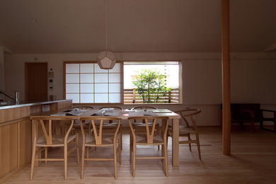Réalisation d'une salle à manger asiatique avec un mur blanc et parquet clair.