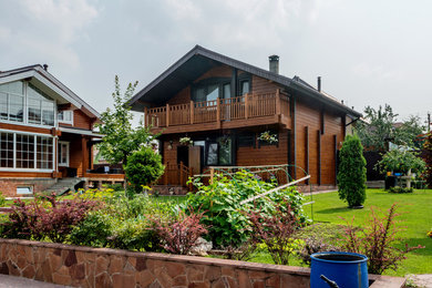 На фото: двухэтажный, деревянный, коричневый дом среднего размера с двускатной крышей с