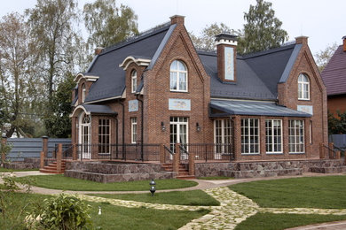 На фото: двухэтажный, кирпичный, коричневый частный загородный дом в классическом стиле с двускатной крышей с