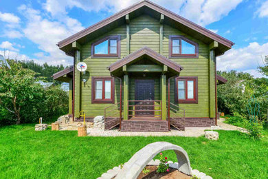 Стильный дизайн: двухэтажный, деревянный, зеленый частный загородный дом среднего размера в классическом стиле с двускатной крышей и металлической крышей - последний тренд