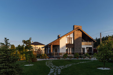 Идея дизайна: двухэтажный, разноцветный частный загородный дом среднего размера в стиле неоклассика (современная классика) с облицовкой из камня, двускатной крышей и черепичной крышей