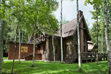 Foto della facciata di una casa marrone rustica con rivestimenti misti e tetto a capanna