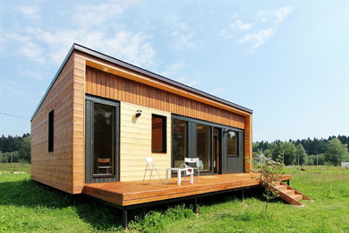 Diseño de fachada de casa marrón nórdica pequeña de una planta con revestimiento de madera, tejado de un solo tendido y tejado de metal