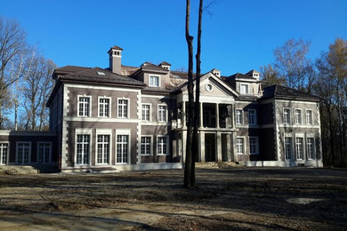 Foto della facciata di una casa grande marrone classica a tre piani con rivestimento in pietra e tetto a padiglione