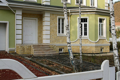 Идея дизайна: двухэтажный, зеленый частный загородный дом в классическом стиле с облицовкой из цементной штукатурки