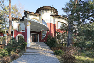 Стильный дизайн: большой, трехэтажный, красный частный загородный дом в стиле фьюжн с облицовкой из цементной штукатурки, двускатной крышей, металлической крышей и входной группой - последний тренд