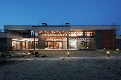 На фото: большой, двухэтажный, разноцветный частный загородный дом в современном стиле с комбинированной облицовкой, плоской крышей и крышей из смешанных материалов с