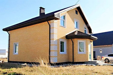 Стильный дизайн: двухэтажный, кирпичный, желтый частный загородный дом среднего размера в классическом стиле с двускатной крышей и металлической крышей - последний тренд